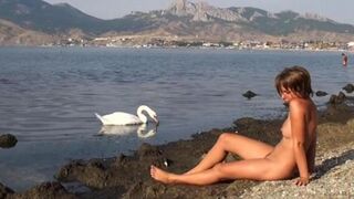 A naked girl is having fun on the riverbank, capturing every moment