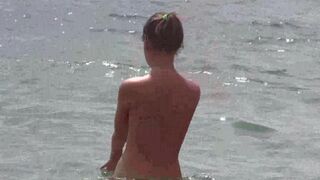 A group of nudists enjoy each other's company on the bare beach