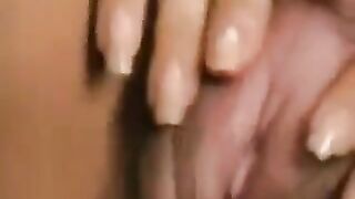 A girl with a large clitoris plays with her hairy pussy