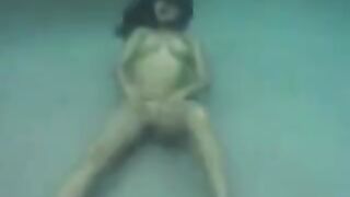 Sex on the ocean floor with a busty brunette, showcasing her fake assets