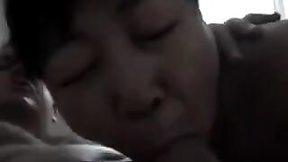 An adult Chinese woman practices her blowjob skills on him, showcasing passion