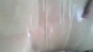 A man masturbates his dick with his hand wearing a condom