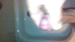 The kid masturbates his dick with his hand while taking a shower