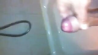 The kid masturbates his dick with his hand while taking a shower