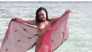 A naked girl bathes in the sea and caresses her body
