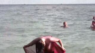 A naked girl bathes in the sea and caresses her body