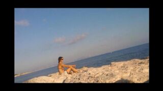 A girl has a sunbath in the nude on the beautiful beach