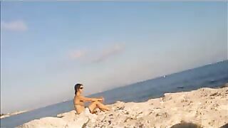 A girl has a sunbath in the nude on the beautiful beach